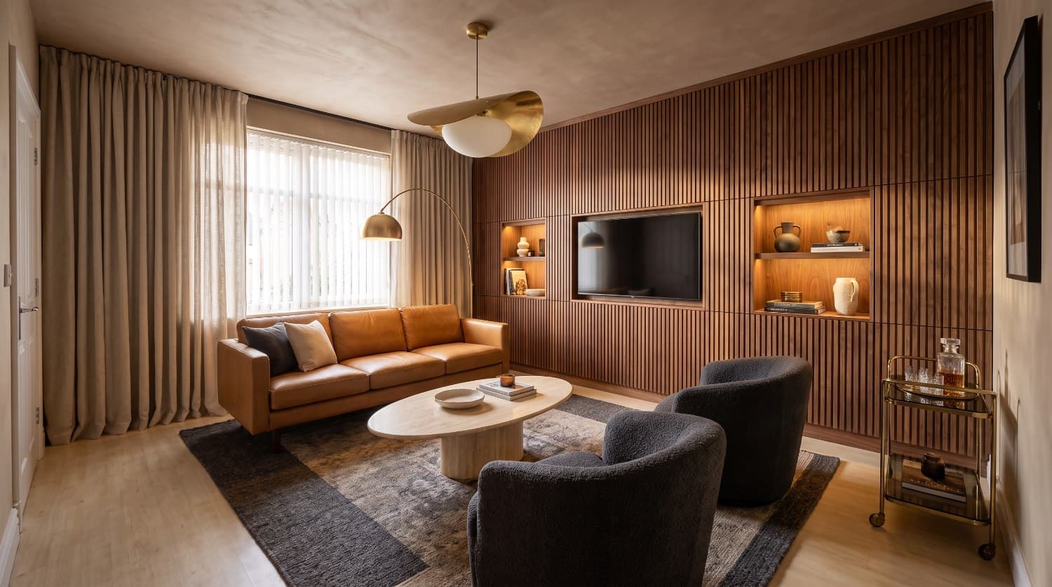 The same living room fully redesigned in the Warm Modern style — same window and doorway, with fluted walnut, camel leather, travertine, brass